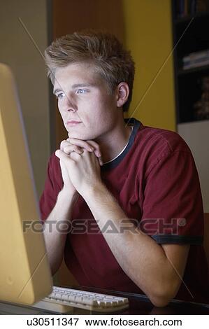 Stock Photo - Man sitting at computer staring at screen. Fotosearch