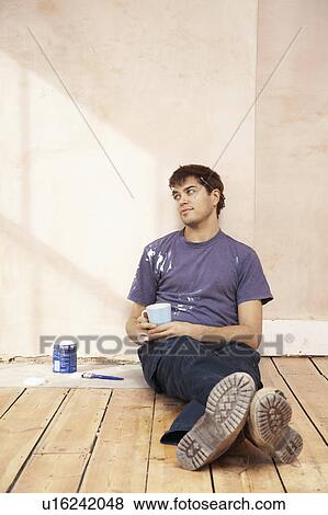 Man sitting on floor of unrenovated room, holding coffee mug View Large Photo Image Stock Photo - Man sitting on floor of unrenovated room, holding coffee mug. Fotosearch