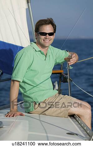 Man sitting on sailboat, drinking white wine, (portrait) View Large Photo Image Stock Image - Man sitting on sailboat, drinking white wine, (portrait). Fotosearch