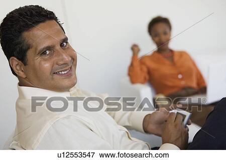 Man sitting on sofa using PDA, portrait, close up View Large Photo Image Stock Photo - Man sitting on sofa using PDA, portrait, close up. Fotosearch