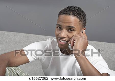 Stock Image - Man sitting using mobile phone. Fotosearch