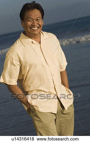 Stock Photo - Man smiling on beach, (portrait). Fotosearch