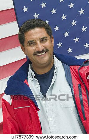 Stock Photo - Man standing in front of American flag, (portrait). Fotosearch