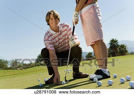 Stock Photo - Man teaching teenage girl to putt. Fotosearch