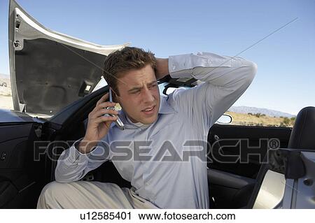 Man using cell phone in broken down sports car at side of road View Large Photo Image Stock Image - Man using cell phone in broken down sports car at side of road. Fotosearch