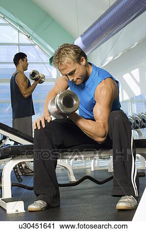 Man using dumbbell in gymnasium View Large Photo Image Stock Image - Man using dumbbell in gymnasium. Fotosearch