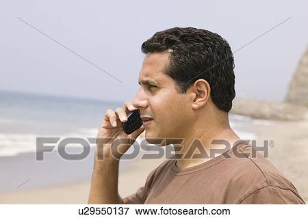 Stock Photo - Man using mobile phone on beach. Fotosearch
