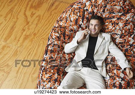Man using mobile phone reclining in beanbag chair, elevated view View Large Photo Image Stock Image - Man using mobile phone reclining in beanbag chair, elevated view. Fotosearch