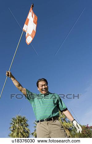 Man waving flag on golf course, (low angle view) View Large Photo Image Stock Image - Man waving flag on golf course, (low angle view). Fotosearch