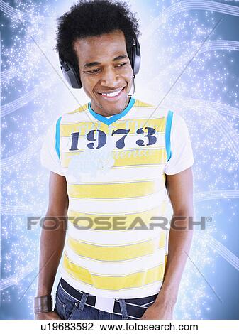 Stock Image - Man wearing headphones in front of lighting effect. Fotosearch