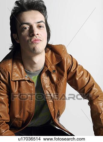 Picture - Man wearing leather coat, sitting in studio. Fotosearch
