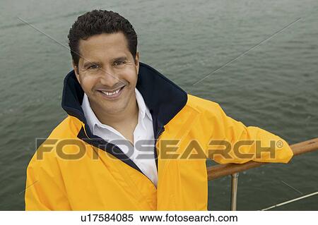 Stock Photography - Man wearing yellow anoraks on yacht, (portrait), (elevated view). Fotosearch