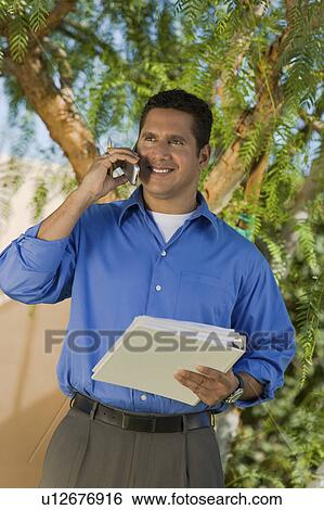 Stock Photograph - Man with folder talking on mobile phone. Fotosearch