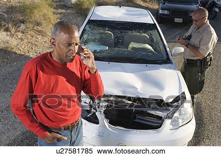 Man with police officer on mobile phone following car accident View Large Photo Image Stock Photography - Man with police officer on mobile phone following car accident. Fotosearch