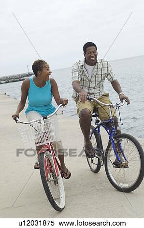 Stock Photography - Middle-aged couple cycling at promenade. Fotosearch