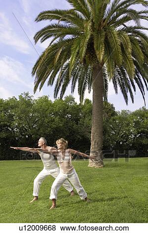Stock Photo - Middle-aged couple doing tai chi in park. Fotosearch