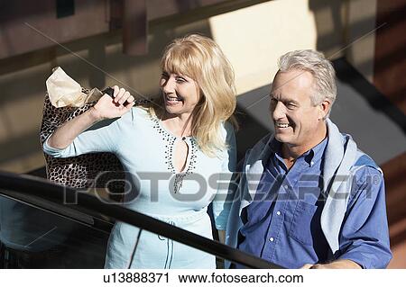 Middle-aged Couple standing side by side outside on Shopping Trip View Large Photo Image Stock Image - Middle-aged Couple standing side by side outside on Shopping Trip. Fotosearch