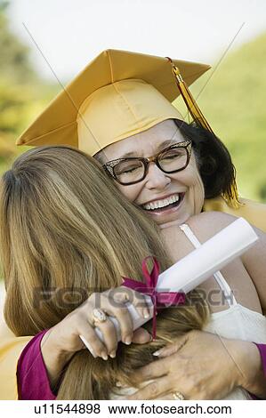 Stock Photo - Middle-aged graduate hugging daughter outside. Fotosearch