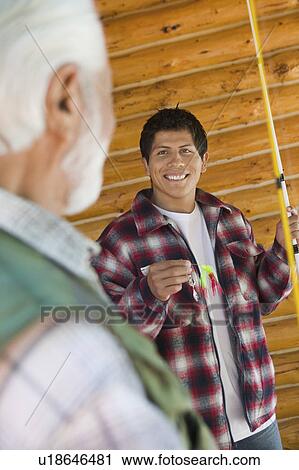 Stock Image - Middle-aged man and son on fishing trip, smiling. Fotosearch