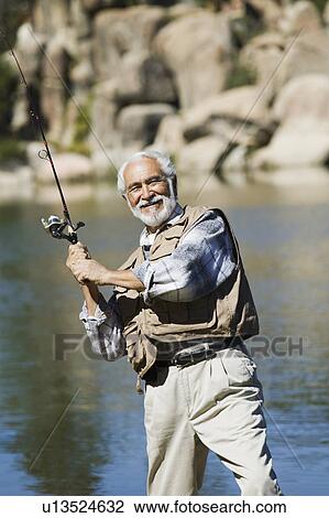 Stock Image - Middle-aged man fly fishing. Fotosearch