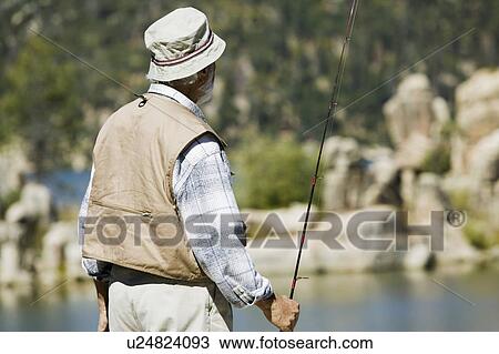 Stock Image - Middle-aged man fly fishing. Fotosearch