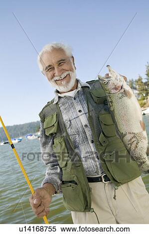 Middle-aged man holding up trout, smiling, (portrait) View Large Photo Image Stock Photography - Middle-aged man holding up trout, smiling, (portrait). Fotosearch