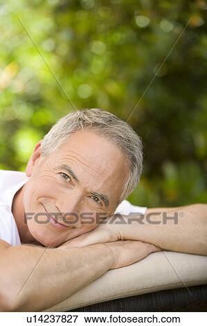 Middle-aged man relaxing on deck chair in garden, portrait View Large Photo Image Stock Photo - Middle-aged man relaxing on deck chair in garden, portrait. Fotosearch