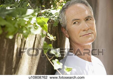 Middle-aged man standing by wall in shade View Large Photo Image Stock Image - Middle-aged man standing by wall in shade. Fotosearch