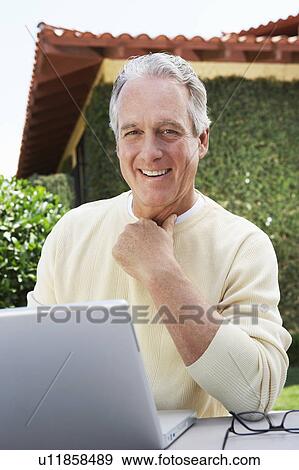 Stock Photo - Middle aged Man Using Laptop in Garden. Fotosearch