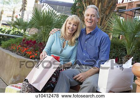 Middle-aged, Smiling couple sitting outside, arms around each other, on Shopping Trip View Large Photo Image Stock Photo - Middle-aged, Smiling couple sitting outside, arms around each other, on Shopping Trip. Fotosearch