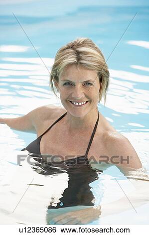 Stock Photograph - Middle-aged woman in swimming pool, portrait. Fotosearch