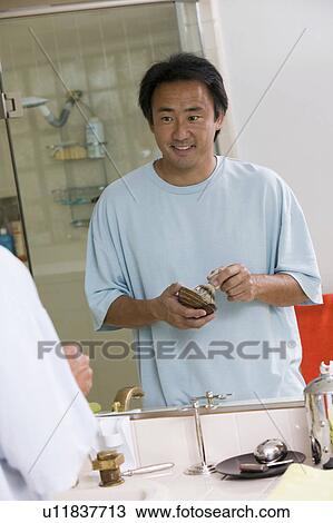 Stock Image - Mirror reflection of Man in bathroom Preparing to Shave. Fotosearch