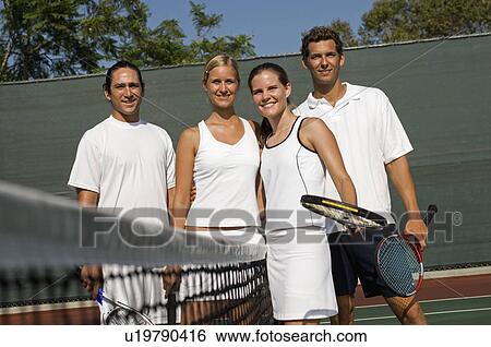 Stock Photograph - Mixed Doubles Tennis Players standing at Net, arms around. Fotosearch