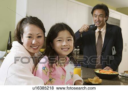 Mother and daughter at breakfast table, father ready for work, portrait View Large Photo Image Stock Photo - Mother and daughter at breakfast table, father ready for work, portrait. Fotosearch
