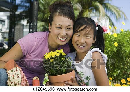 Stock Image - Mother and daughter gardening, (portrait). Fotosearch