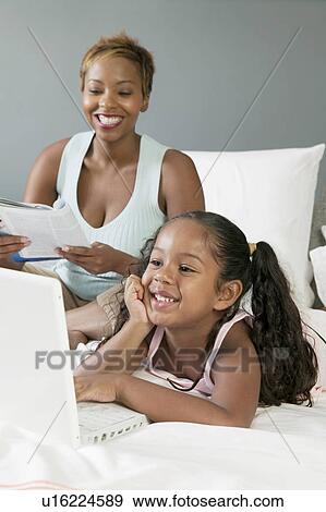 Mother and Daughter on bed Looking at Laptop View Large Photo Image Stock Photo - Mother and Daughter on bed Looking at Laptop. Fotosearch