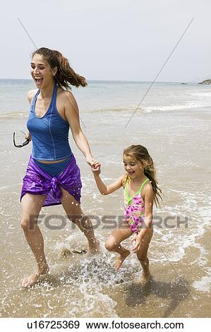 Stock Photo - Mother and Daughter Running Through Water on Beach. Fotosearch