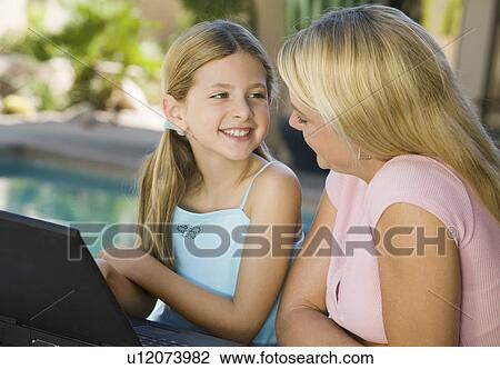 Stock Image - Mother and Daughter Using Laptop on Patio. Fotosearch
