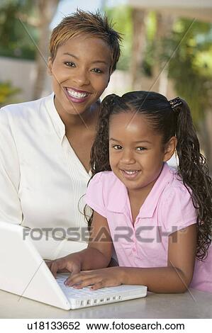 Stock Image - Mother and Daughter Using Laptop on patio, portrait. Fotosearch