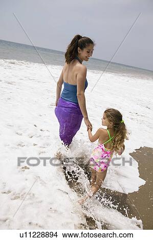 Mother and daughter walking through surf View Large Photo Image Picture - Mother and daughter walking through surf. Fotosearch