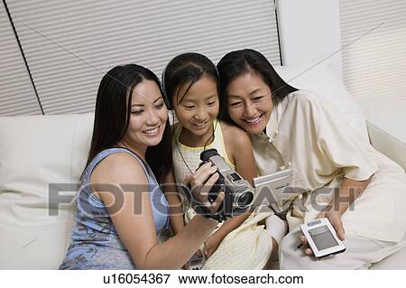 Mother and Daughters on sofa looking at Video Camera screen View Large Photo Image Stock Photo - Mother and Daughters on sofa looking at Video Camera screen. Fotosearch