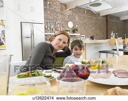 Mother and son (5-6) at kitchen table, (portrait) View Large Photo Image Picture - Mother and son (5-6) at kitchen table, (portrait). Fotosearch