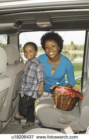 Stock Photo - Mother and young son together in open car doorway with basket. Fotosearch