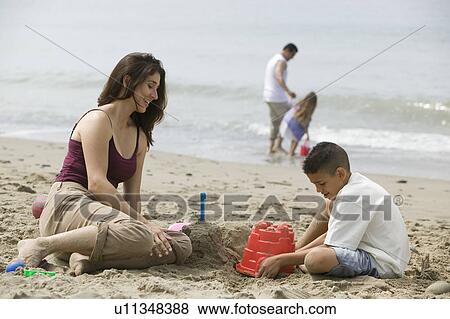 Stock Photo - Mother building sandcastles with son on beach. Fotosearch