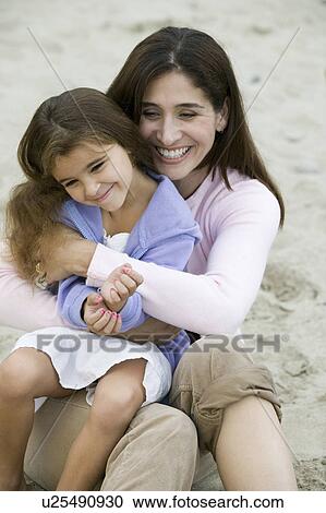 Stock Image - Mother embracing daughter on beach. Fotosearch