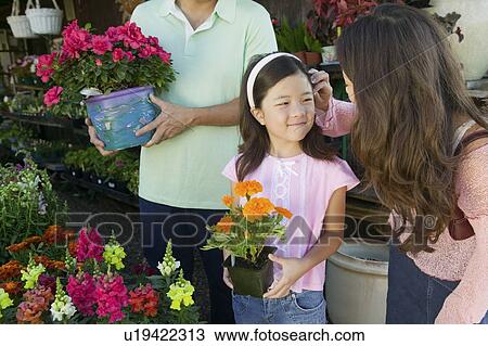 Stock Image - Mother fixing hair of daughter in plant nursery. Fotosearch