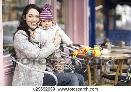Mother holding baby on lap sitting in outdoor cafe View Large Photo Image Stock Photo - Mother holding baby on lap sitting in outdoor cafe. Fotosearch
