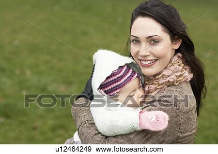 Mother in park, holding sleeping baby View Large Photo Image Stock Photo - Mother in park, holding sleeping baby. Fotosearch