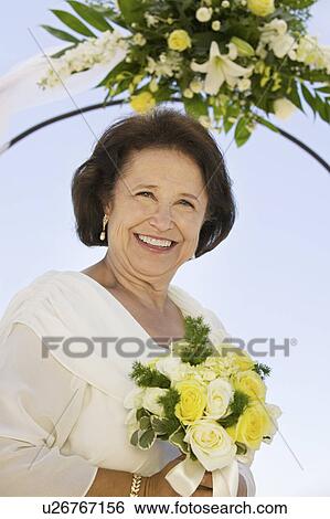 Stock Photograph - Mother of bride with bouquet, outdoors, (portrait). Fotosearch