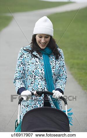 Mother pushing stroller in park View Large Photo Image Stock Photo - Mother pushing stroller in park. Fotosearch